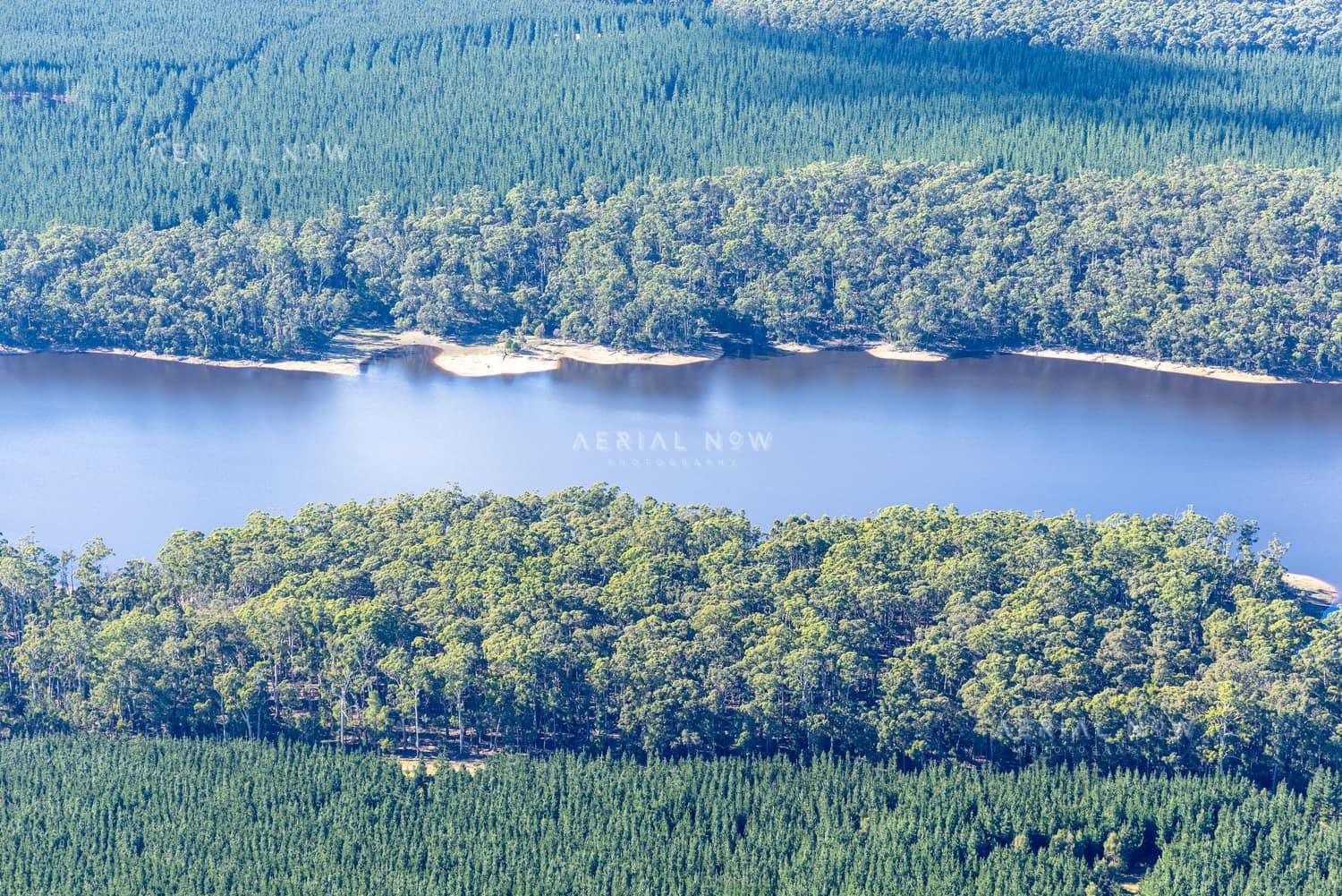 Aerial view of Bostock Reservoir with forested shoreline and pine plantations near Spargo Creek, Victoria.