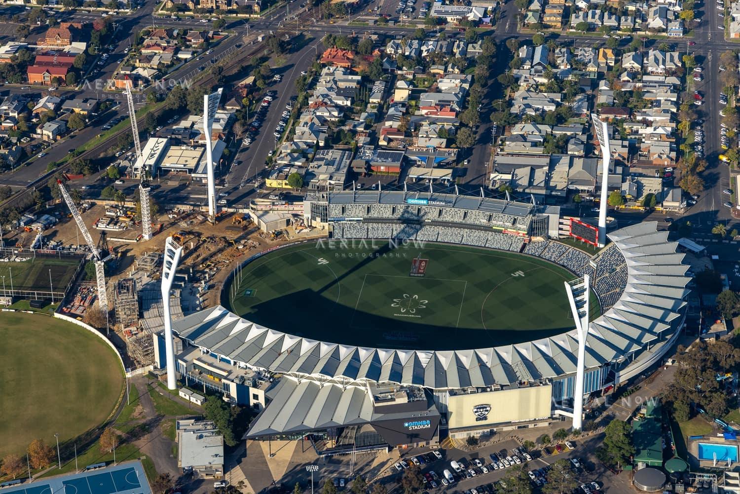 Aerial view of GMHBA Stadium at Kardinia Park in South Geelong, showing construction cranes and earthworks beside the stadium with surrounding streets and housing.