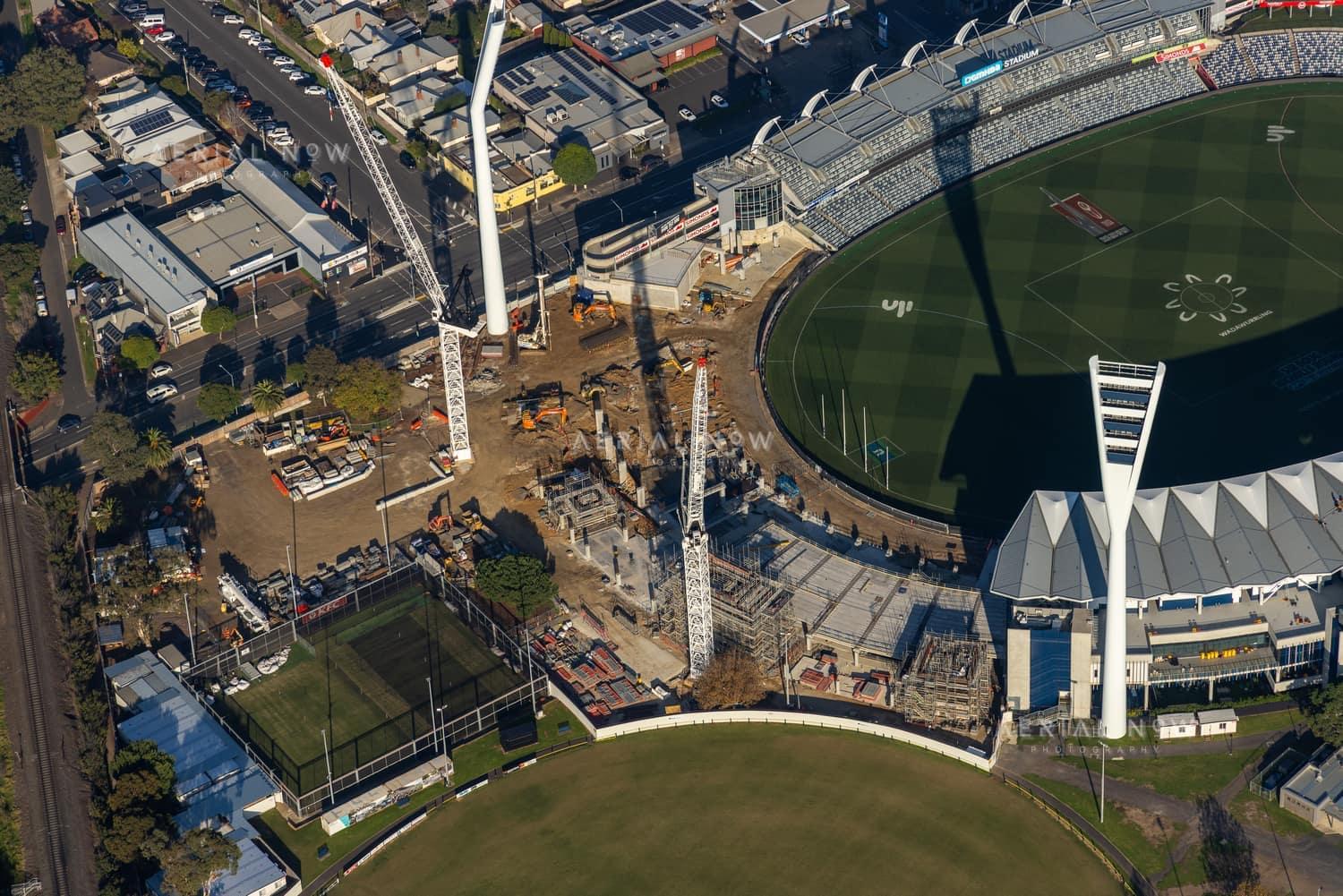 Aerial view of GMHBA Stadium and Kardinia Park in South Geelong with tower cranes, construction works, grandstands and surrounding sports fields visible.