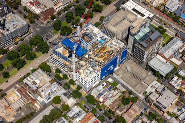 Aerial view of Australian Catholic University’s Saint Teresa of Kolkata Building under construction in Fitzroy on 7 February 2022, with cranes and incomplete upper levels visible.