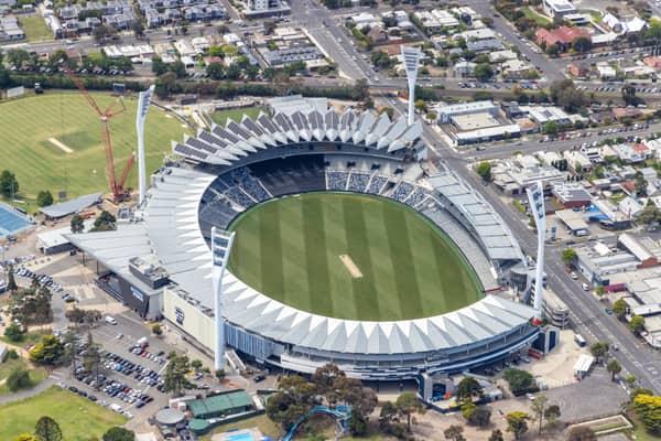 Aerial view of GMHBA Stadium at Kardinia Park in South Geelong, showing the oval, grandstands, light towers, surrounding streets and cranes near the precinct.
