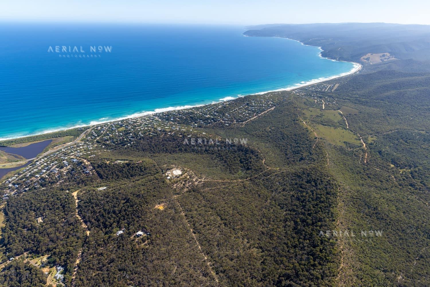 Aerial view of Fairhaven Beach in Fairhaven VIC, showing the surf coastline, residential streets, coastal bushland and blue ocean along the Great Ocean Road region.