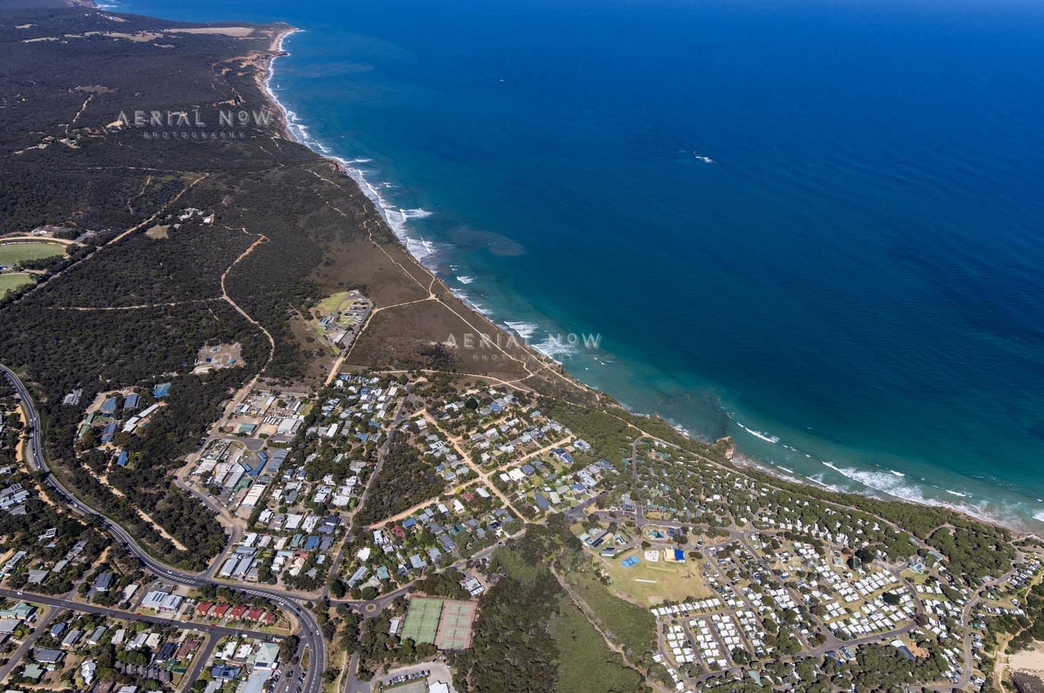 Aerial view of Anglesea coastline, residential streets, bushland reserves and ocean surf in Anglesea, Victoria.