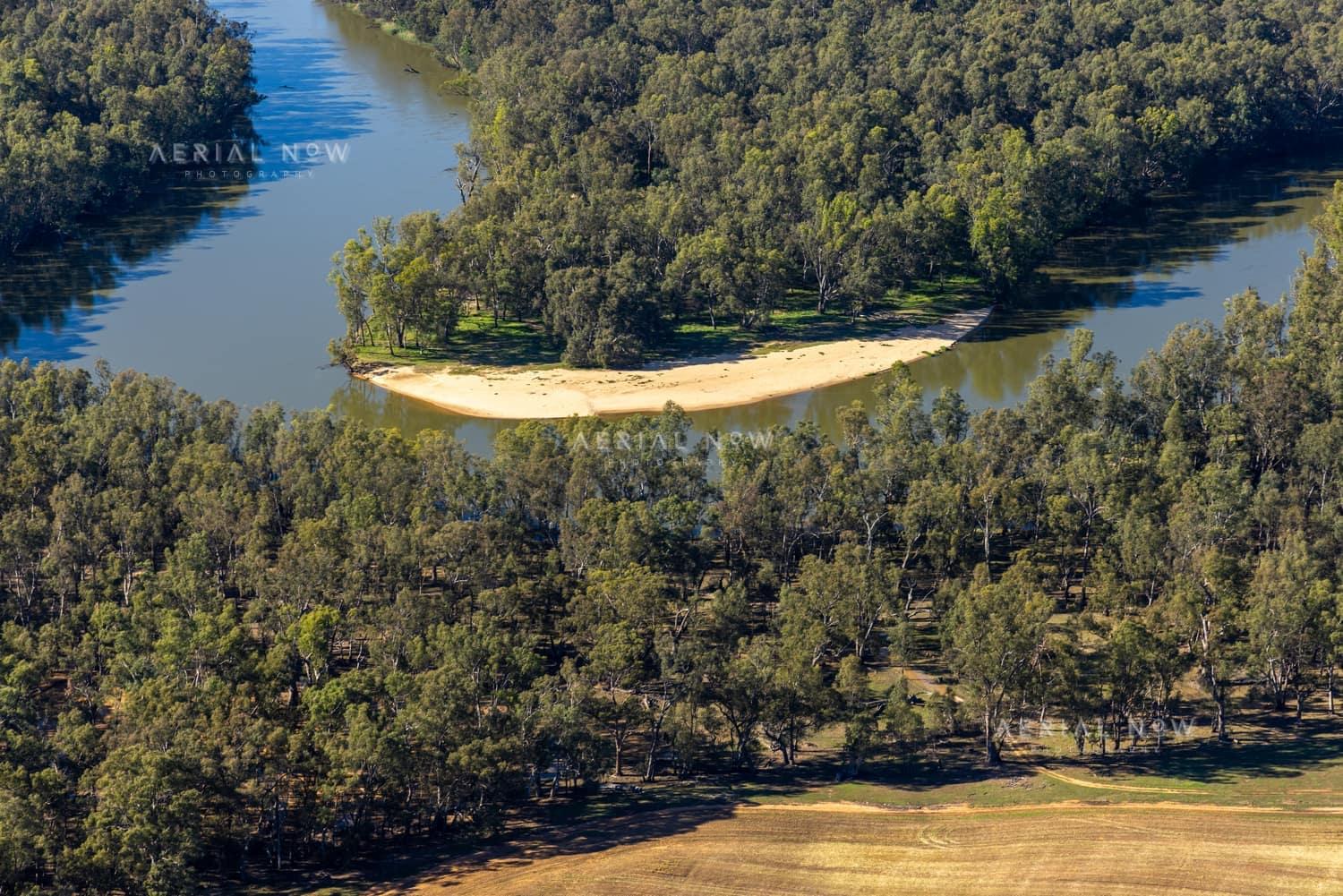 Aerial view of a Murray River bend with a sandy point, river red gum woodland and farmland near Cobram East, Victoria.
