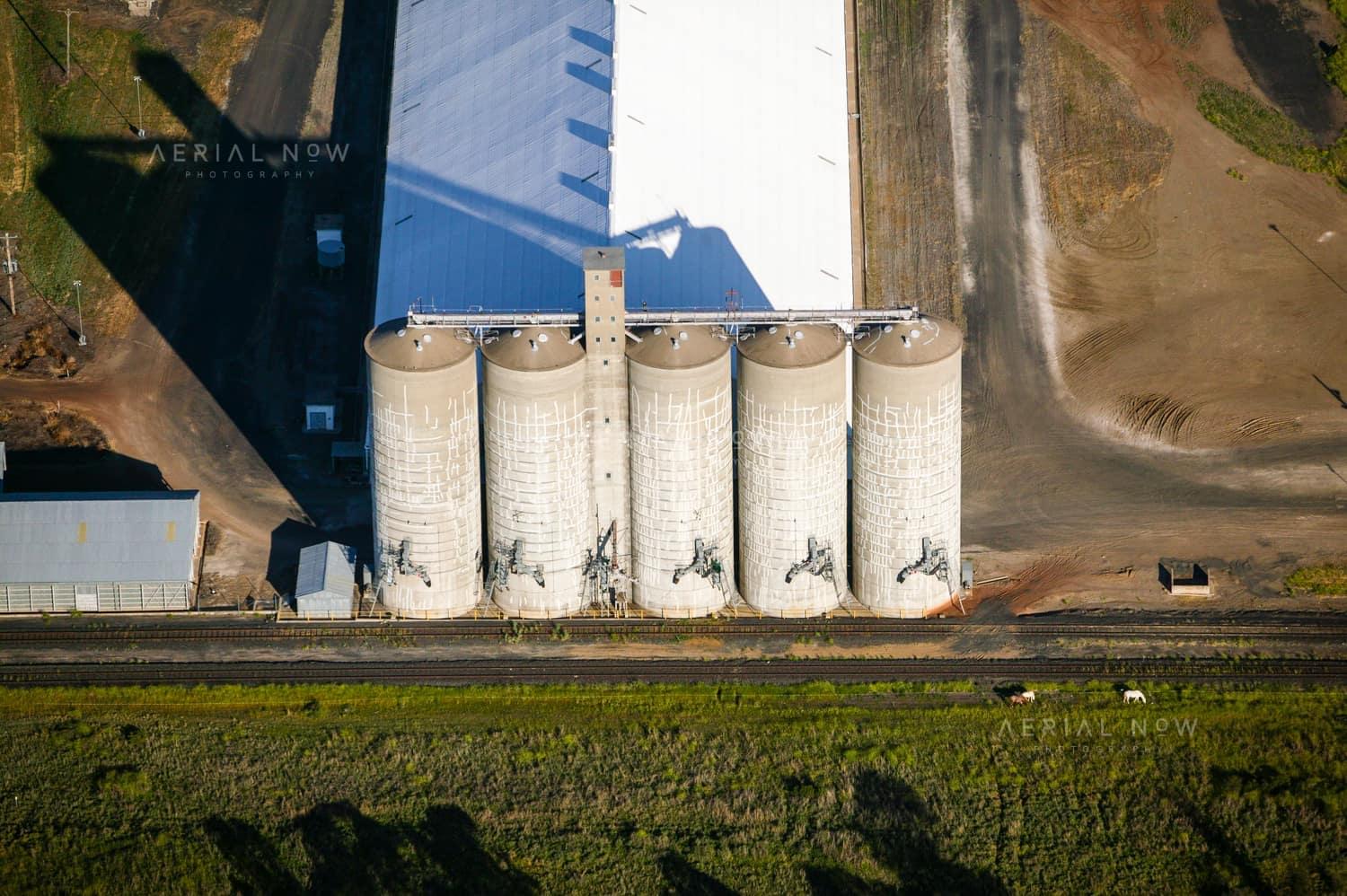 Aerial view of the GrainCorp Moree grain terminal, showing concrete silos, bulk grain storage shed and rail siding in Moree, New South Wales.