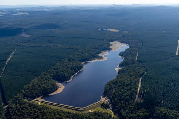 Aerial view of Bostock Reservoir in Bunding, Victoria, showing the dam wall, curving shoreline and surrounding forest plantations.